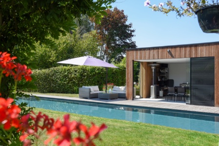 poolhouse naast het zwembad met parasol in aangelegde tuin