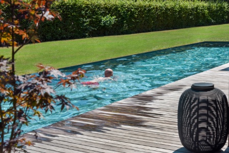 man zwemt in zwembad in eigen tuin