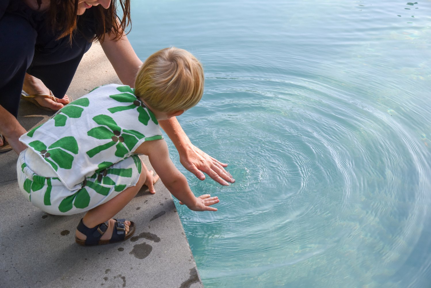 moeder en kind spelen aan de rand van een bio zwembad of biopool in een parktuin 