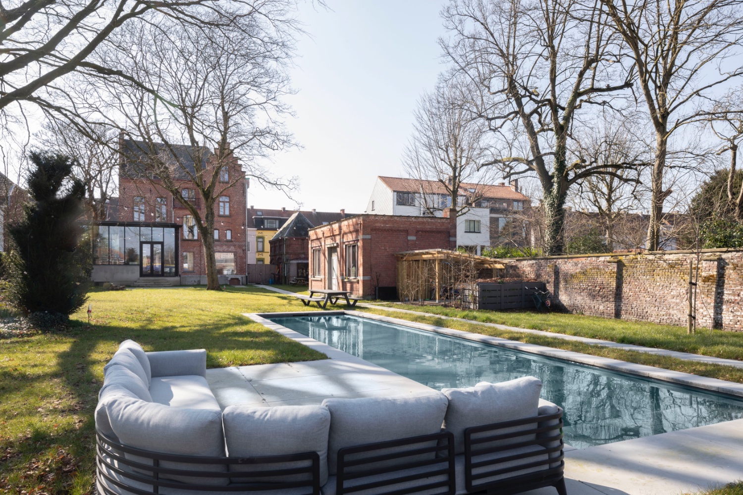 foto van achteraan in de parktuin met zicht op de achtergevel van een herenwoning met een biopool