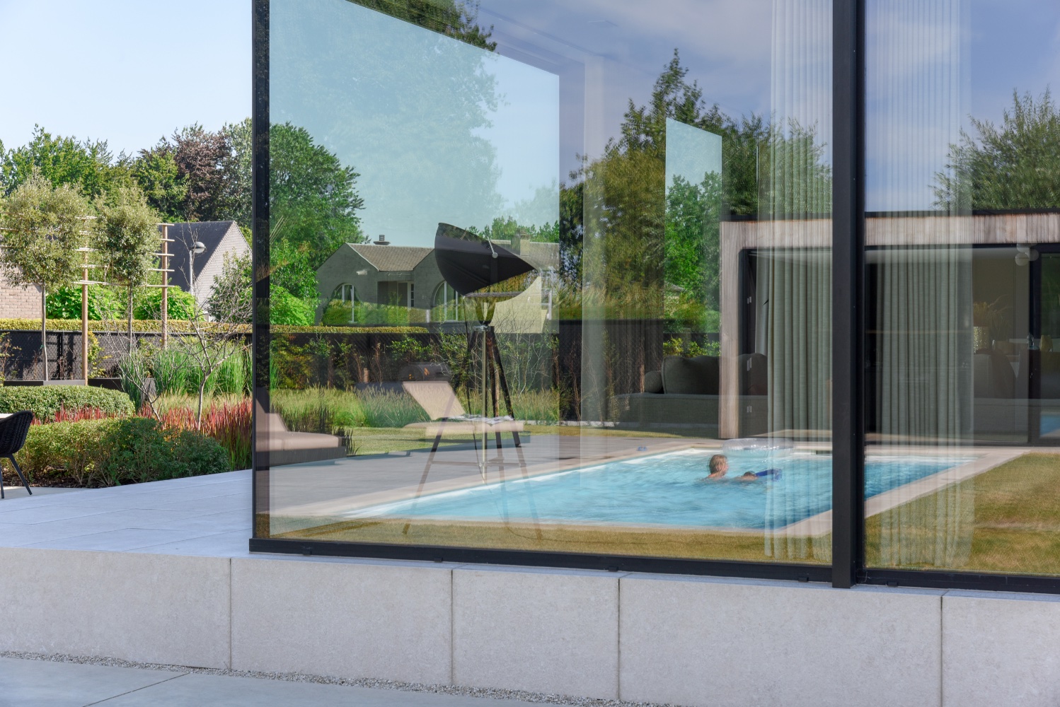 reflectie in het raam van een strak wit zwembad bij moderne villa