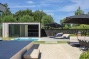 poolhouse, tuin en tarwes naast een strak wit zwembad bij moderne villa