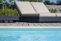 ligzetels naast een strak wit zwembad bij moderne villa