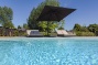 parasol en ligzetels naast een strak wit zwembad bij moderne villa