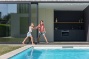 kindjes spelen in poolhouse strak wit zwembad bij moderne villa
