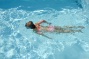 kind zwemt in een strak wit zwembad bij moderne villa