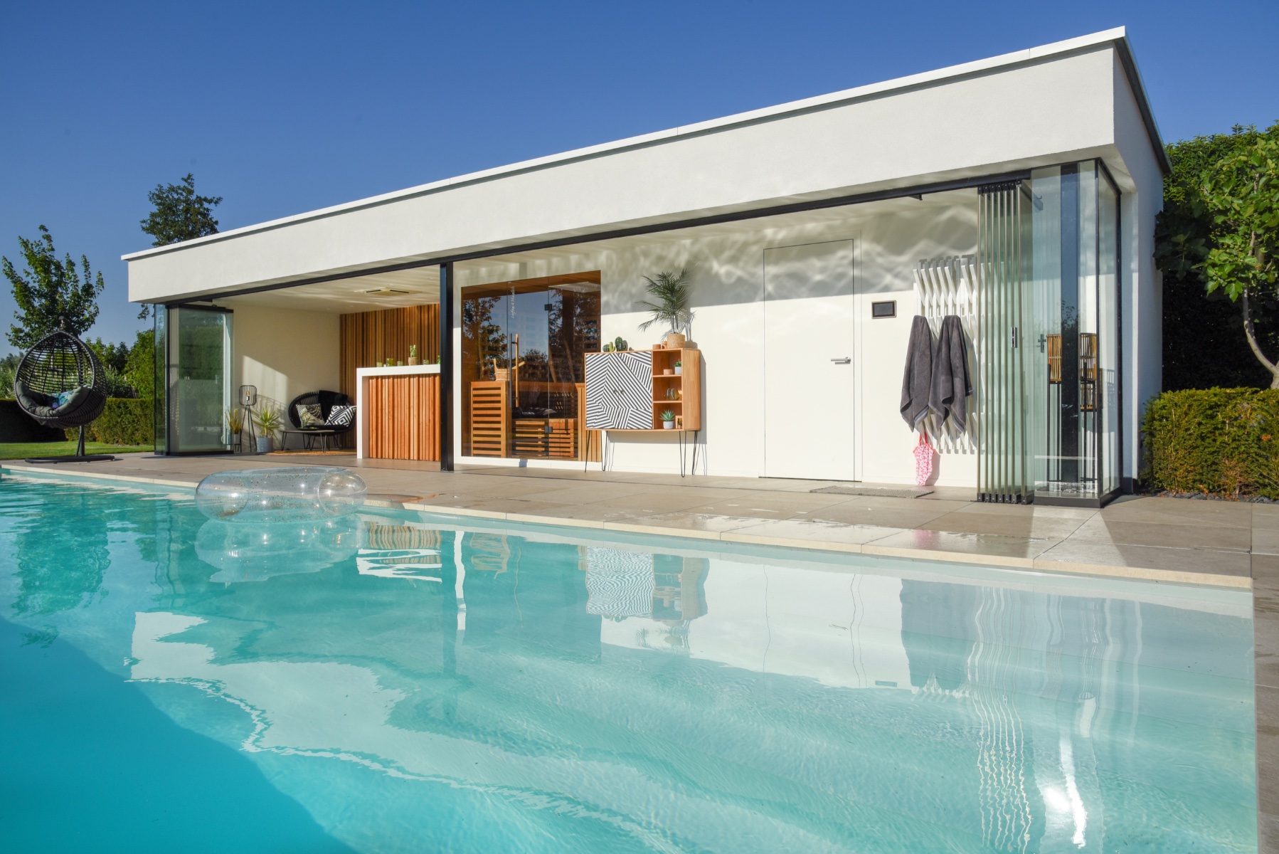 strak en modern poolhouse met een tikkeltje vintage naast het zwembad