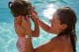 Kleuter gaat zwemmen in een biopool en mama helpt met de duikbril
