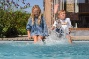kids spelen zittend op de natuursteen rand van het zwembad