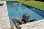 naast het zwembad staat een kunstwerk beeld van man lijkt uit het zwembad te kruipen