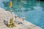 een fles wijn met twee glazen aan de rand van het zwembad